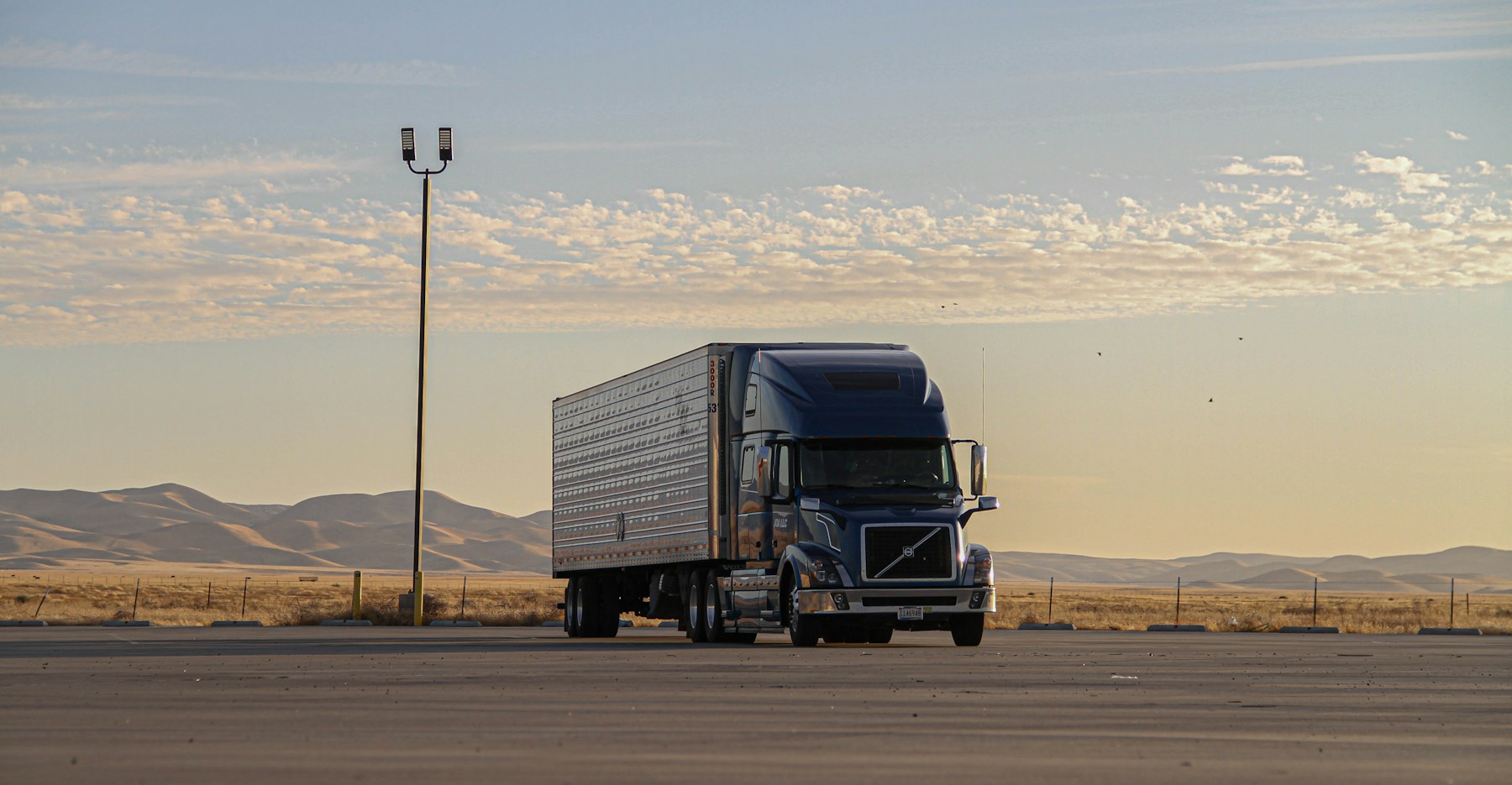 Black American semi truck beside an open desert landscape